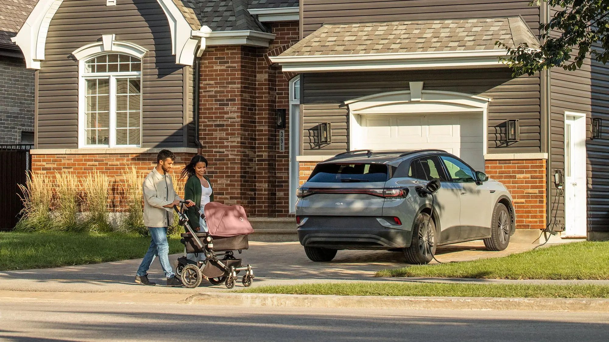 An electric vehicle recharges while a couple with a stroller takes a walk.