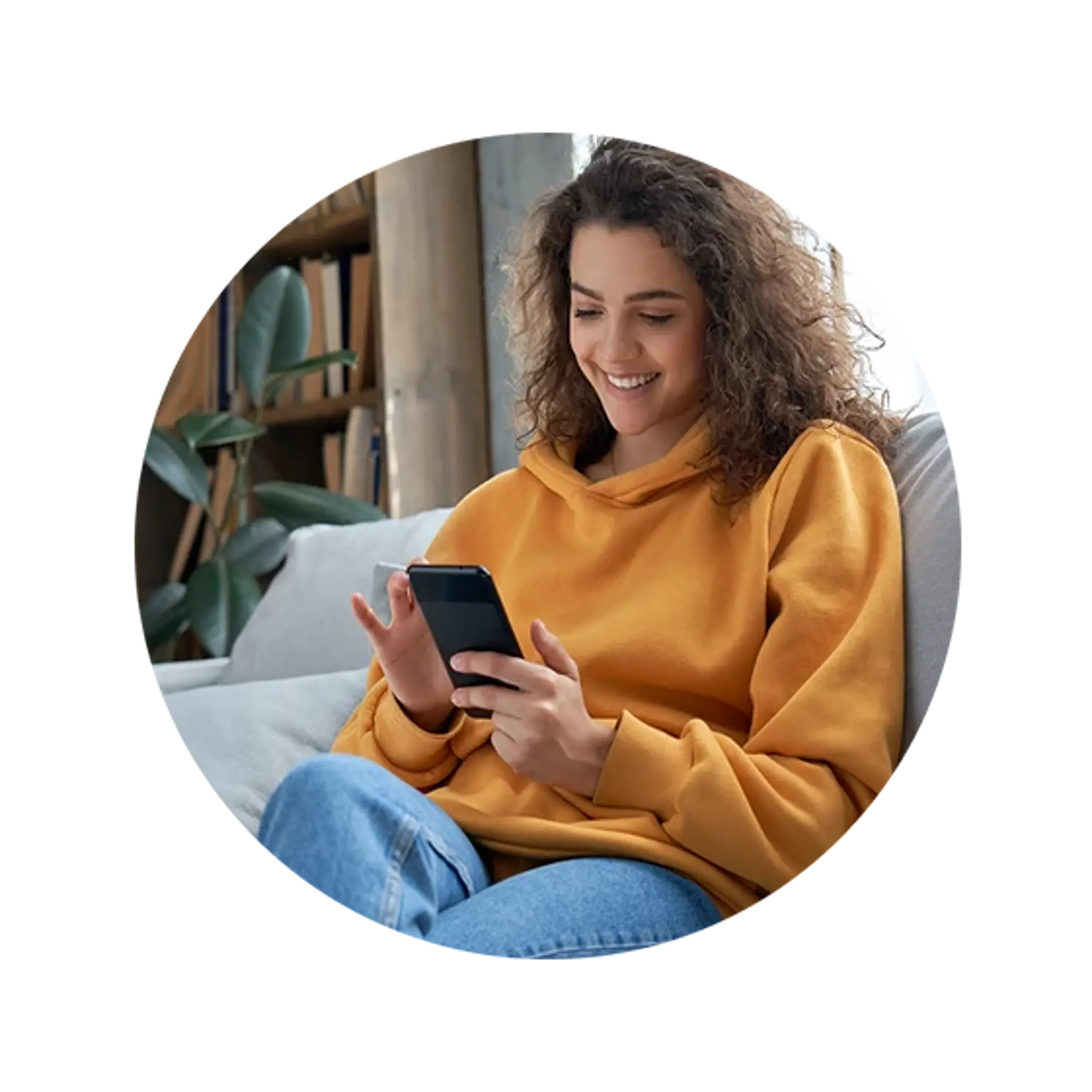 Woman sitting on a couch, wearing an orange sweater, using a smartphone.