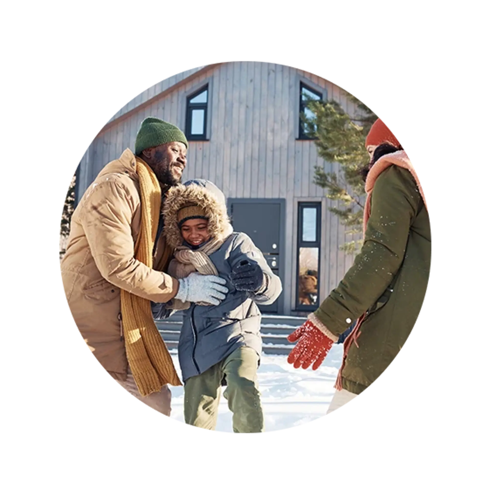 Three people in winter coats are playing in the snow in front of a wooden cabin.