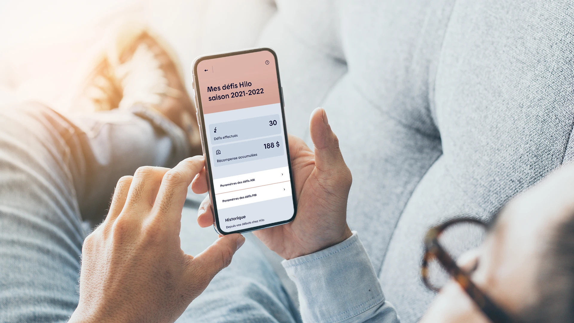 Personne utilisant l’application mobile Hilo pour suivre sesévénements de pointe et ses économies d’énergie.